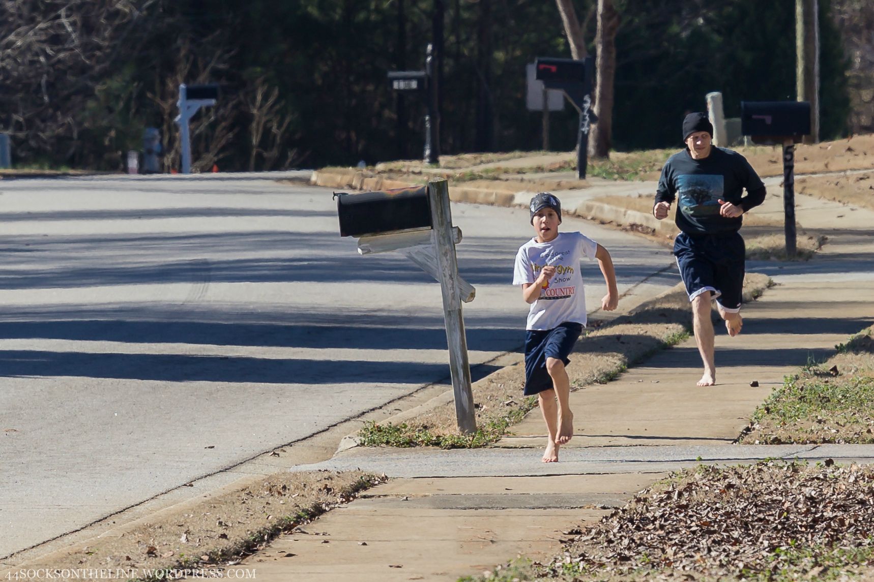 Man and boy running on residential sidewalk Society for Barefoot Living.
